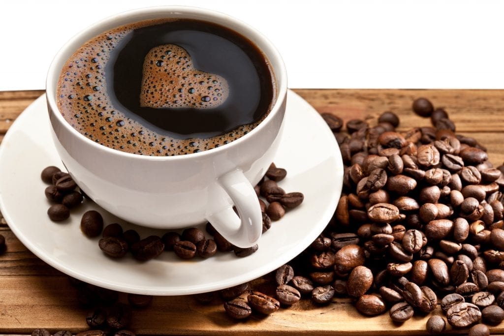 Coffee cup and saucer on a wooden table. Foam in the form of the heart.
